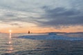 A small boat among icebergs. Sailboat cruising among floating icebergs in Disko Bay glacier during midnight sun Greenland