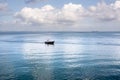 Small boat with a person on board is floating in a peaceful body of water.