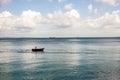 Small boat with a person on board is floating in a peaceful body of water.