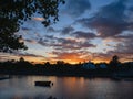 Small boat in river Corrib at sunset. Stunning cloudy sky in the background. Silhouette of town building. Warm and cool tone. Royalty Free Stock Photo