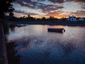 Small boat in river Corrib at sunset. Stunning cloudy sky in the background. Silhouette of town building. Warm and cool tone. Royalty Free Stock Photo