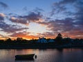 Small boat in river Corrib at sunset. Stunning cloudy sky in the background. Silhouette of town building. Warm and cool tone. Royalty Free Stock Photo