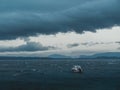 Small boat sailing in the stormy ocean under the dark cloudy sky Royalty Free Stock Photo