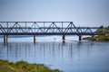 A small boat sails along the river in a summer sunny day under a railway bridge Royalty Free Stock Photo