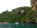 Small boat with tourists stopped near a huge rock so that tourists could understand the ocean and see the underwater world Royalty Free Stock Photo