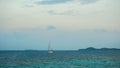 A small boat yacht sailing in the middle of sea with small island in distance as background