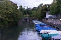 Small boats with raincovers in canal with tree and water reflection for fishing and sailing