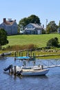 Small boats are tied to a dock in front of waterfront houses of Westport Point, MA