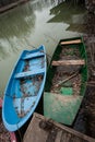 Small boats tied to a wooden dock full of fallen leaves on lake Royalty Free Stock Photo