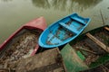 Small boats tied to a wooden dock full of fallen leaves on pond