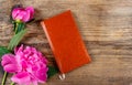 Small book and lush pink peonies on wooden table