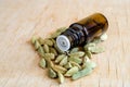 Small bottle with essential cardamon oil on the wooden background. Cardamom seeds close up. Aromatherapy, spa and herbal medicine Royalty Free Stock Photo