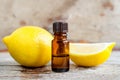 Small bottle of essential lemon oil on the old wooden background. Aromatherapy, spa and herbal medicine ingredients.