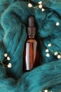 Small bottle with essential oil or serum on blue wool with gypsophila