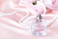 A small bottle of perfume on a soft pink background of fabric and roses Royalty Free Stock Photo