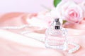 A small bottle of perfume on a soft pink background of fabric and roses Royalty Free Stock Photo