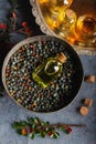 Small bottle of Pistacia terebinthus oil on the bowl of dried seeds on dark wooden background