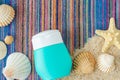 Small bottle with sunscreen lotion on the colorful beach towel with sand and seashells. Summer skin care and sun protection Royalty Free Stock Photo