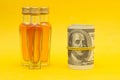 Small bottles with alcohol on a yellow background and money dollars, the proceeds from the sale of alcohol, close-up, photography