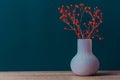 Small bouquet of red flowers in vintage vase on wood table blue navy wall background. Styled stock image mockup for text artwork Royalty Free Stock Photo