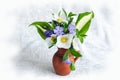 A small bouquet of spring flowers in a clay vase on a light background Royalty Free Stock Photo