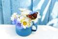 A small bouquet with wild flowers, daisies and cornflowers in a vintage mug and a butterfly. Royalty Free Stock Photo