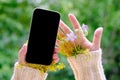 Small bouquets of simple wildflowers in the sleeves of a sweater, a modern mobile phone with a blank black screen, mocap, in hands
