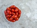 Small bowl filled with red grape tomatoes on a gray marble background