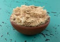 Small bowl filled with shredded slippery elm bark on a tabletop side view