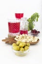 Small bowl with green olives. Nuts and olives, healthy snacks. Appetizer time. Cranberries juice. Mediterranean diet.