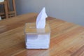 Small box with white tissues inside sits on a wooden table in a cafe or restaurant Royalty Free Stock Photo