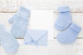 Small boy blue socks, gloves, blank card and evelop on white wooden background. Flat lay. Royalty Free Stock Photo