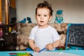 a small boy draws on sheets of paper lying on the table with colored pencils Royalty Free Stock Photo