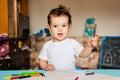 a small boy draws on sheets of paper lying on the table with colored pencils Royalty Free Stock Photo