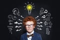 Small boy in glasses and lightbulb on blackboard background in classroom Royalty Free Stock Photo