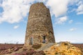 Small boy hand on hips in front of ruin of Windmill.