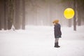 A small boy holding a big yellow balloon in the winter forest. Birthday boy with balloon. Winter walks with snow