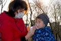 A small boy with illness bronchial asthma getting treatment with aerosol inhaler from his mama outdoors Royalty Free Stock Photo