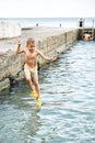 Small boy jumps from stone pier to sea touching water Royalty Free Stock Photo