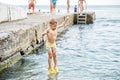 Small boy jumps from stone pier to sea touching water Royalty Free Stock Photo