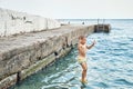 Small boy jumps from stone pier to sea touching water Royalty Free Stock Photo