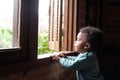 Small boy looking out of the window in times of staying iindoors