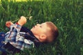 A small a boy lying down on the grass holds in the hands of flowers dandelion . Royalty Free Stock Photo