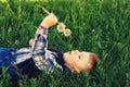 A small a boy lying down on the grass holds in the hands of flowers dandelion . Royalty Free Stock Photo