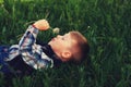 A small a boy lying down on the grass holds in the hands of flowers dandelion . Royalty Free Stock Photo
