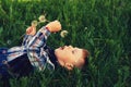 A small a boy lying down on the grass holds in the hands of flowers dandelion . Royalty Free Stock Photo