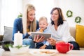 A small boy with mother and grandmother at home at Christmas time, using tablet. Royalty Free Stock Photo