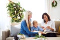 A small boy with mother and grandmother looking at photos at home at Christmas time. Royalty Free Stock Photo