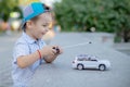 A small boy plays with a toy car on radio control holding a remote control