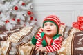 Newborn baby girl dressed in gnome costume lying on white fur carpet among christmas decorations. Royalty Free Stock Photo